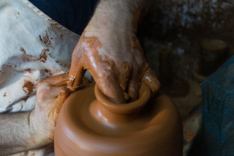 Potter's hands skillfully shaping clay on a pottery wheel, showcasing craftsmanship and creativity.
