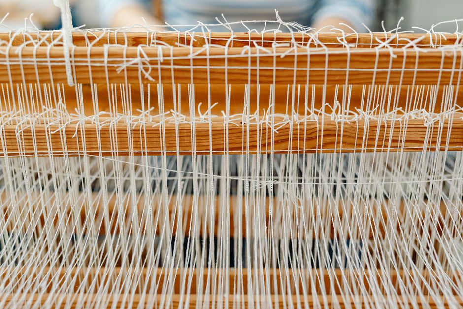 Detailed close-up of a wooden loom with white threads, showcasing traditional weaving.
